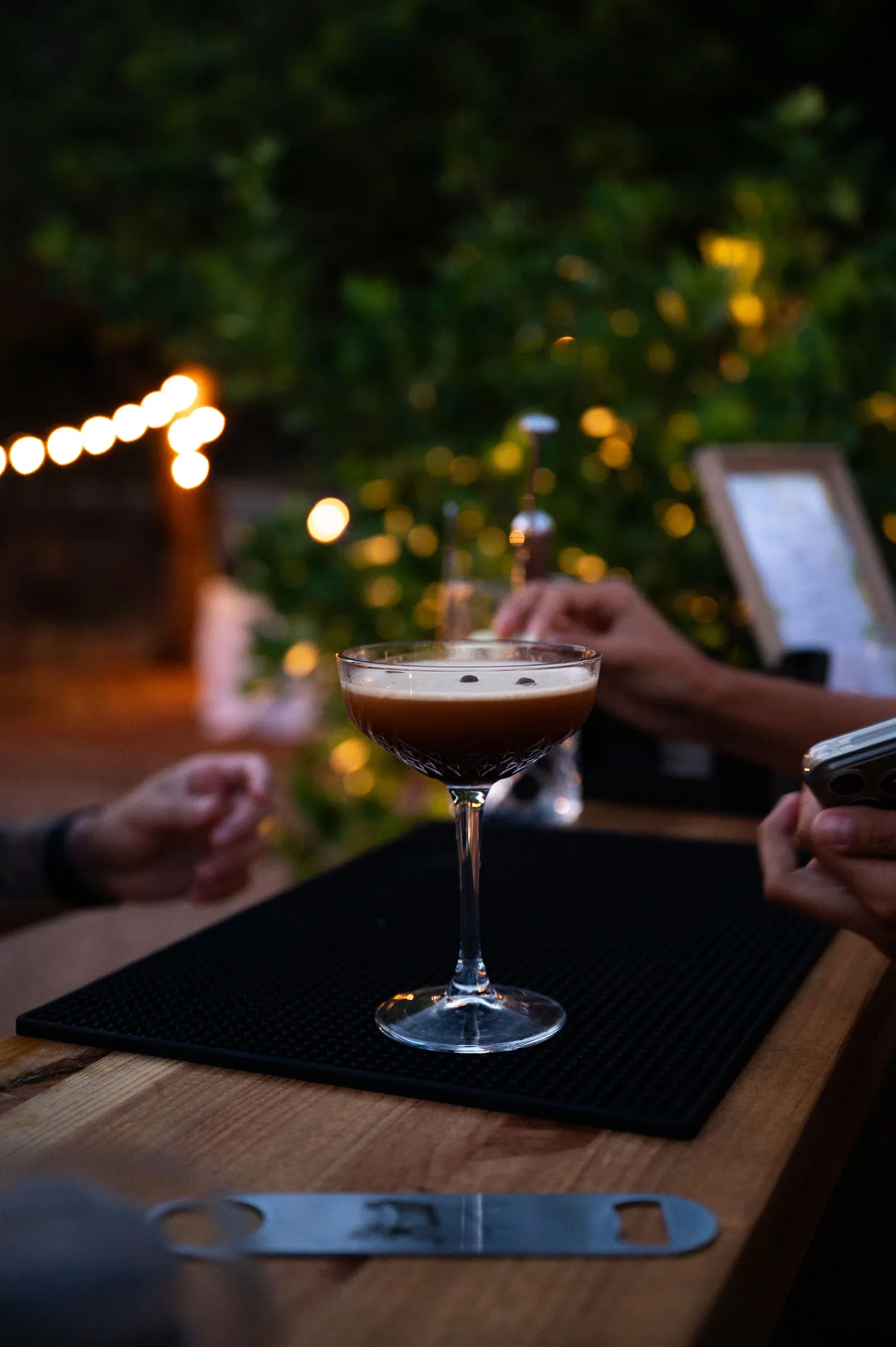 Un espresso martini servido bajo guirnaldas de luces